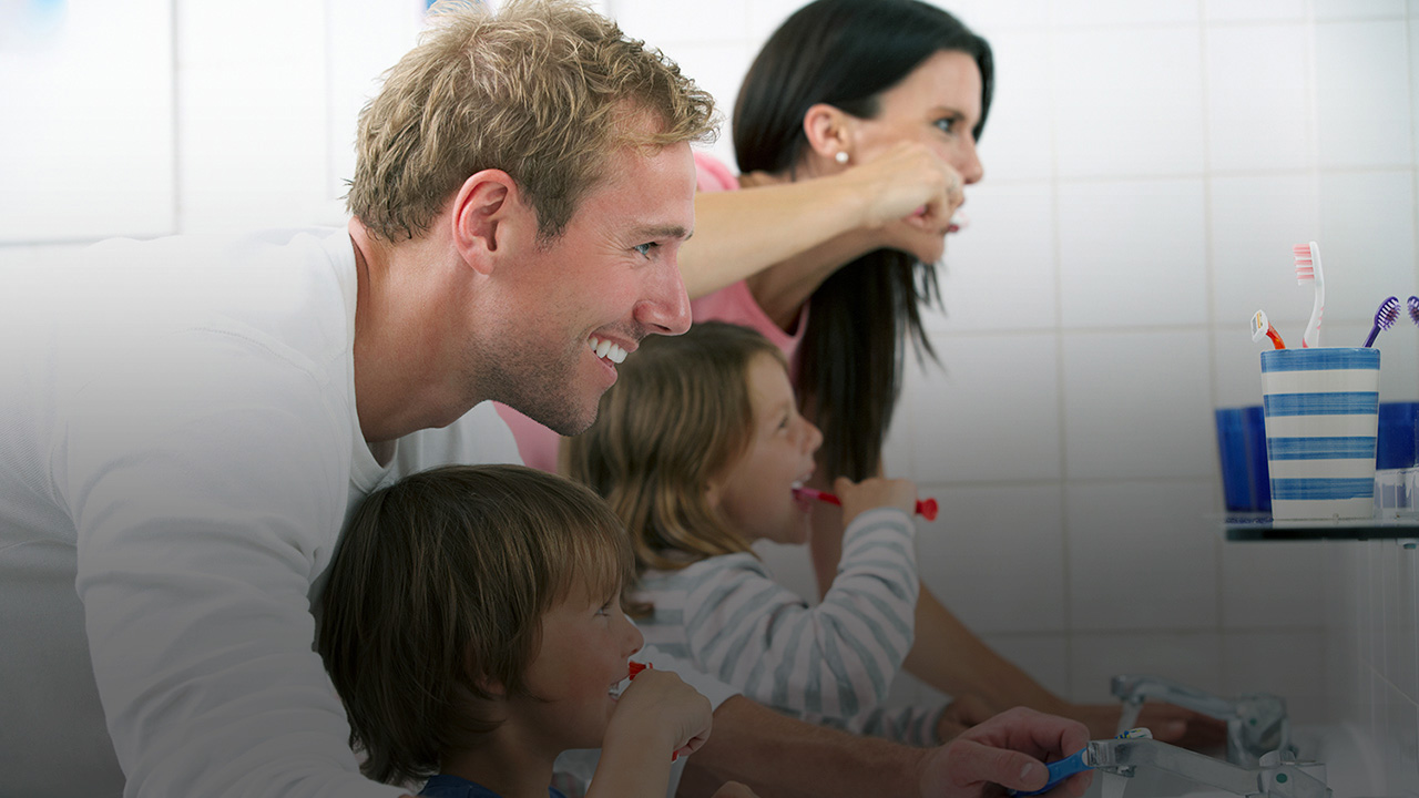 Eine Familie steht im Badezimmer und putzt sich die Zähne.